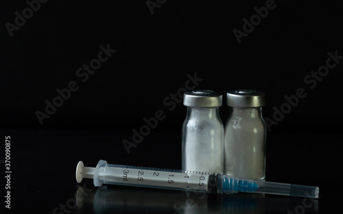 jeringas de tres mililitros con frascos de medicamento con polvo blanco en un fondo negro