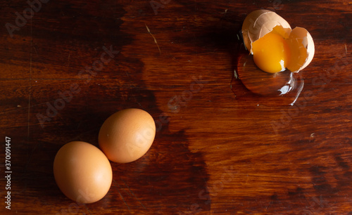 huevos de color café sobre una mesa de madera barnizada con un huevo estrellado. Huevo roto sobre una mesa de madera