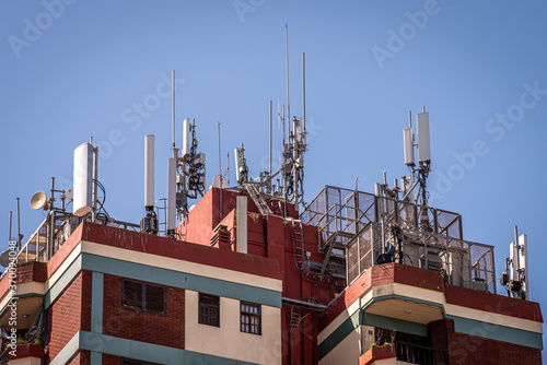 Mobile phone base station antennas placed over the rooftops of a building © Andres Conema