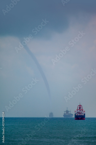 Tornado on the Mediterranean Sea and many cargo ships.