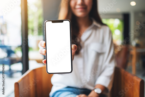 фотографія Mockup image of a woman holding and showing mobile phone with blank white screen