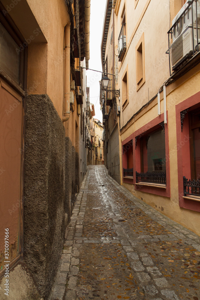 Cityscape. History and architecture. Colorful buildings with ancient design. View of the narrow alley and wet street after rain, in Toledo, Spain.