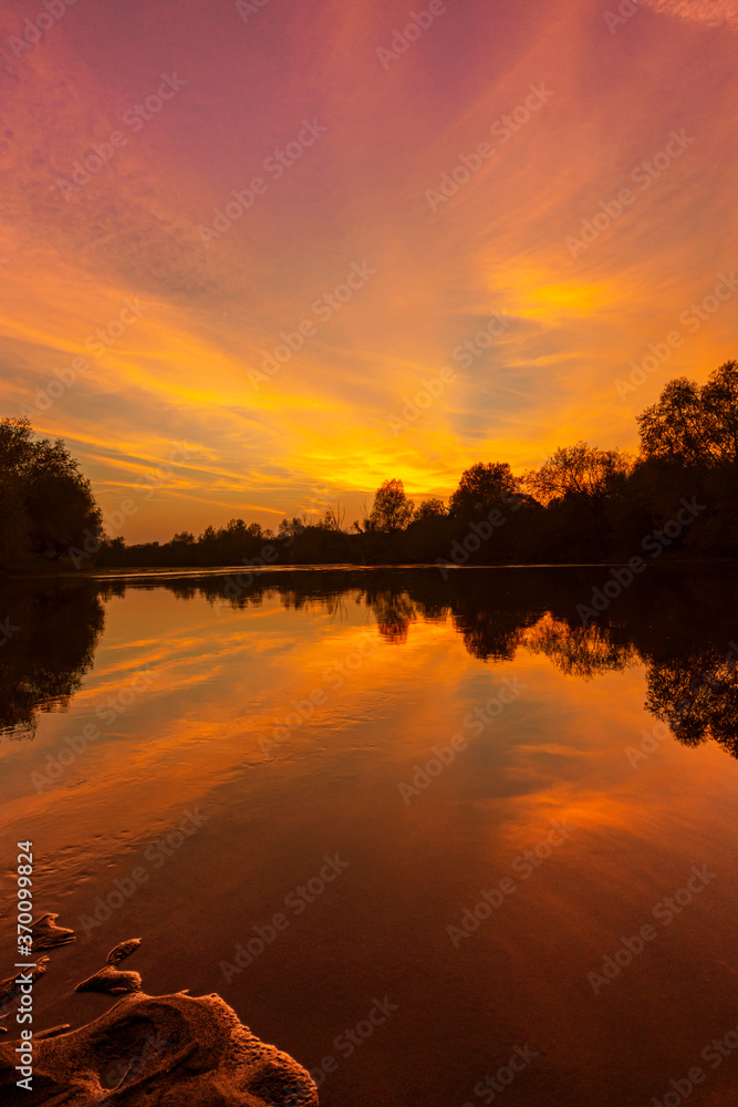 Obraz premium Wild, colorful sunset over tranquill river in a remote area in Europe