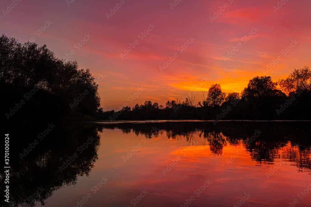 Obraz premium Wild, colorful sunset over tranquill river in a remote area in Europe