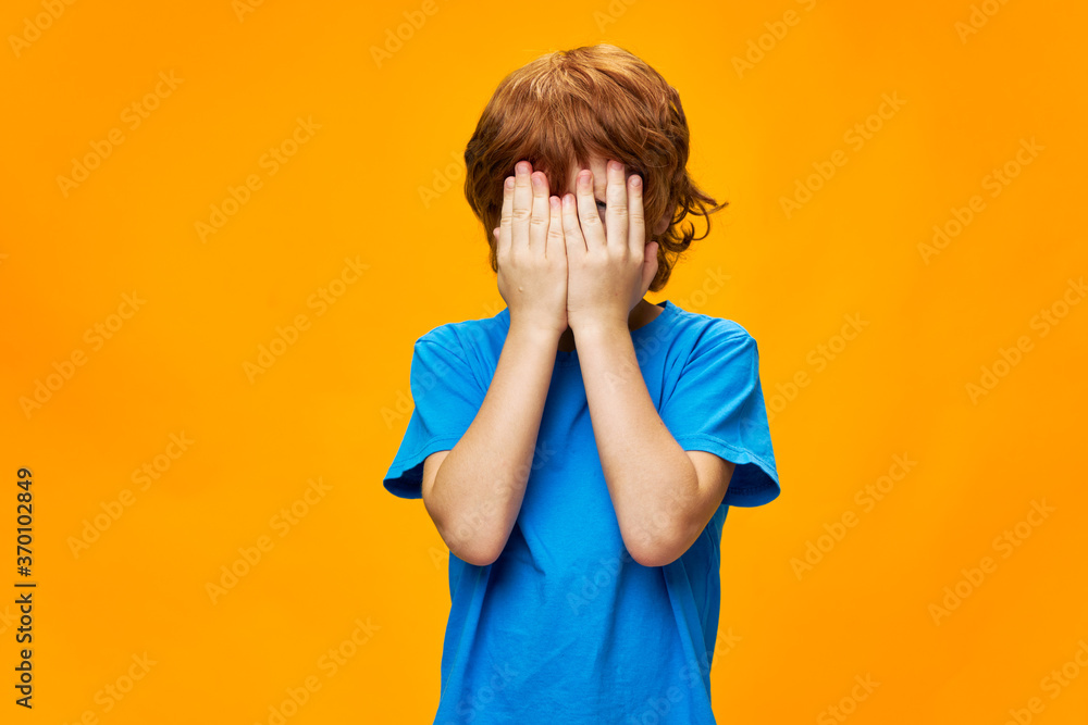 The boy covered his face with his hands red hair tears blue t-shirt The boy covered his face with his hands red hair tears blue t-shirt