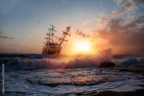 Sailing ship in storm sea against heavy sunset clouds