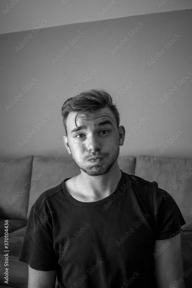 Fototapeta premium Black and White, Young white man wearing t-shirt standing over isolated green background puffing cheeks with funny face. Mouth inflated with air, crazy expression.