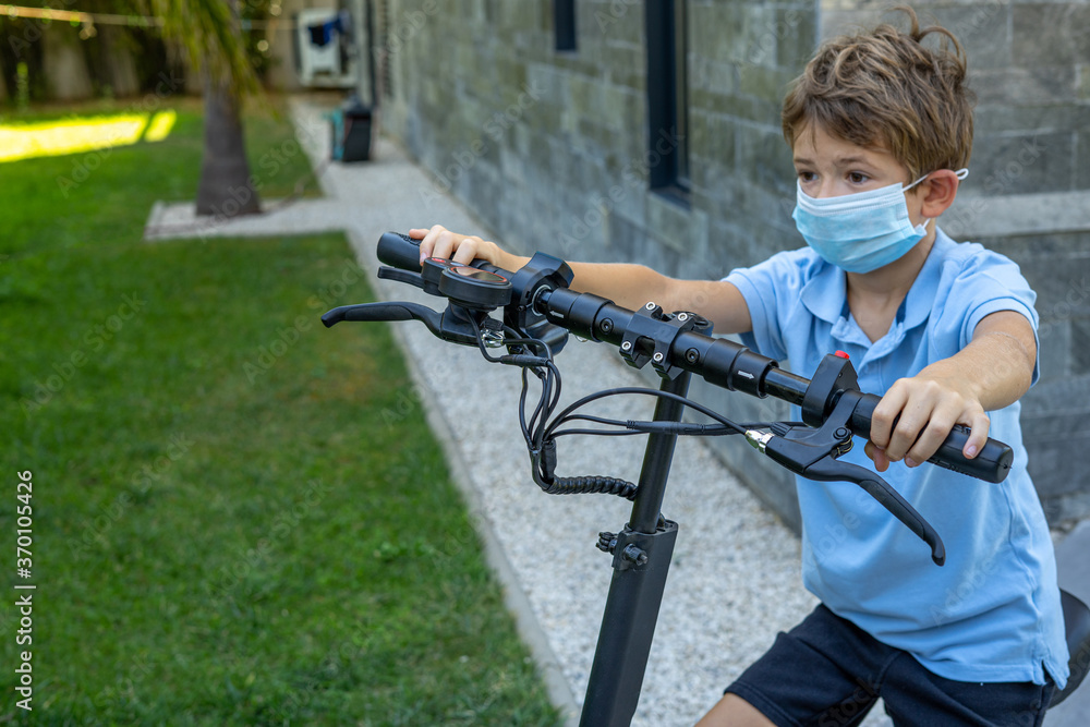 Obraz premium Boy with protective mask with his new electric scooter. Eco friendly vehicle concept . Soft background