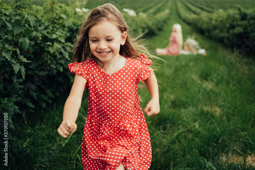 Young Mom with her Little Daughter Dressed Alike in Red Polka Dot Dress  Having Fun Time in the Field Outside the City  Motherhood and Childhood Concept