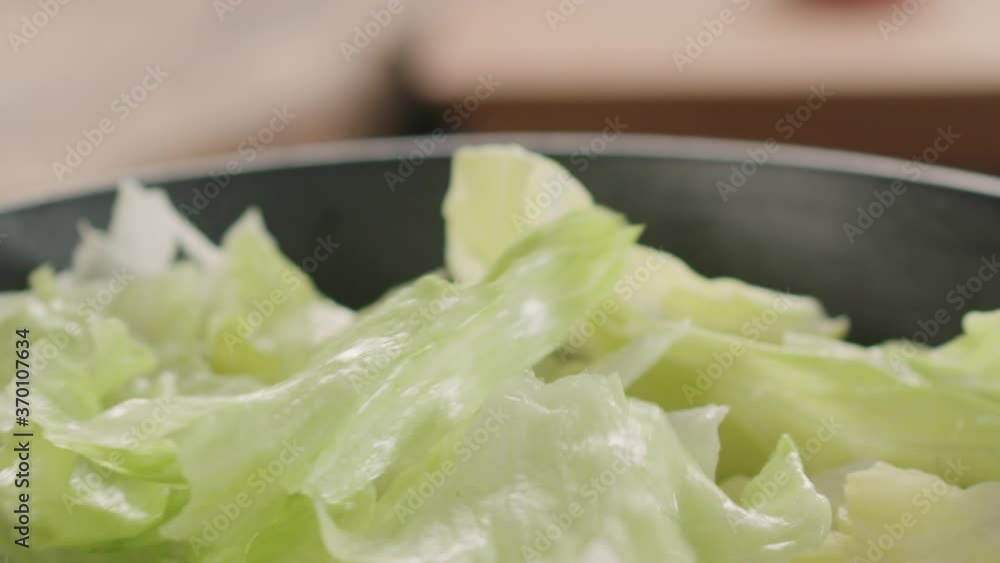 Slow motion slide shot of iceberg leaves fall into salad bowl Slow motion slide shot of iceberg leaves fall into salad bowl