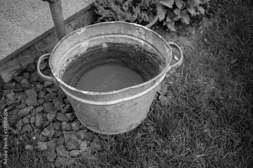 Metal bucket filled with water and dirt on the bottom of it in a park AM Metal bucket filled with water and dirt on the bottom of it in a park AM