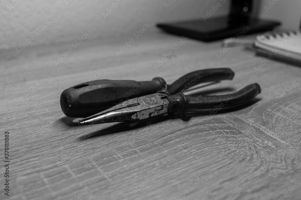 Blue screwdriver and yellow pliers placed on a wooden desk Blue screwdriver and yellow pliers placed on a wooden desk