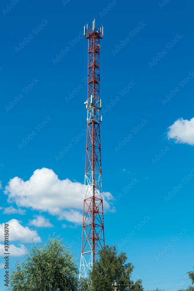 red and white cell tower in front of blue sky red and white cell tower in front of blue sky
