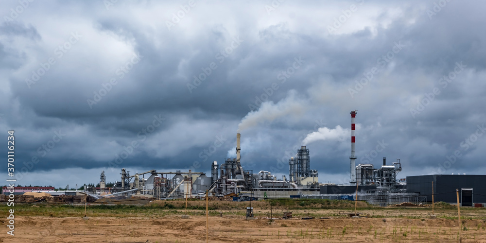 pipes of woodworking enterprise plant sawmill against a gloomy gray sky. Air pollution concept. Panorama of industrial landscape environmental pollution waste of thermal power plant