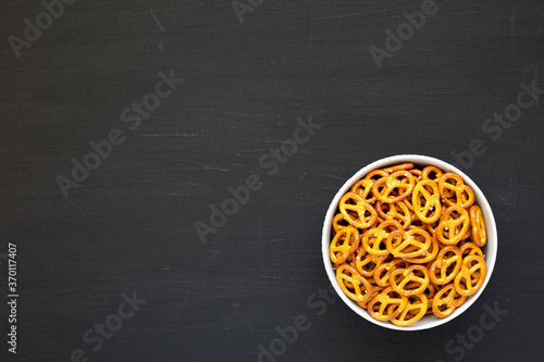Crispy Pretzel Crackers in a Gray Bowl on a black surface, top view. Copy space.