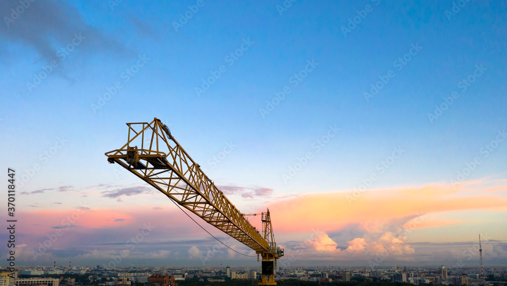 Building crane and buildings under construction against evening sky