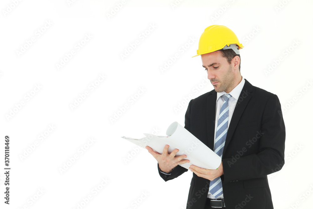 Handsome and smart engineer in black suit Wearing a yellow safety engineer hat with hand holding Construction drawing papers and serious in work isolated on yellow background. Copy Space Handsome and smart engineer in black suit Wearing a yellow safety engineer hat with hand holding Construction drawing papers and serious in work isolated on yellow background. Copy Space