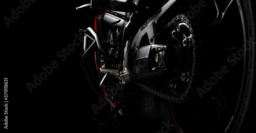 Side view of red sports motorcycle in a spotlight on a black background