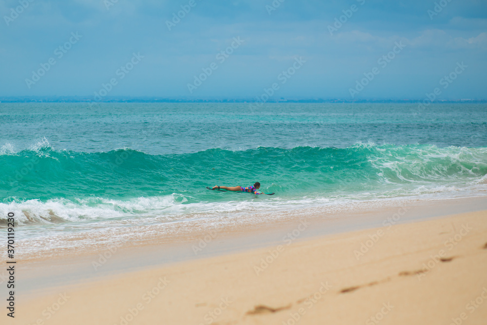 Sexy slim girl riding on surf board in the ocean. Healthy active lifestyle in summer vocation.