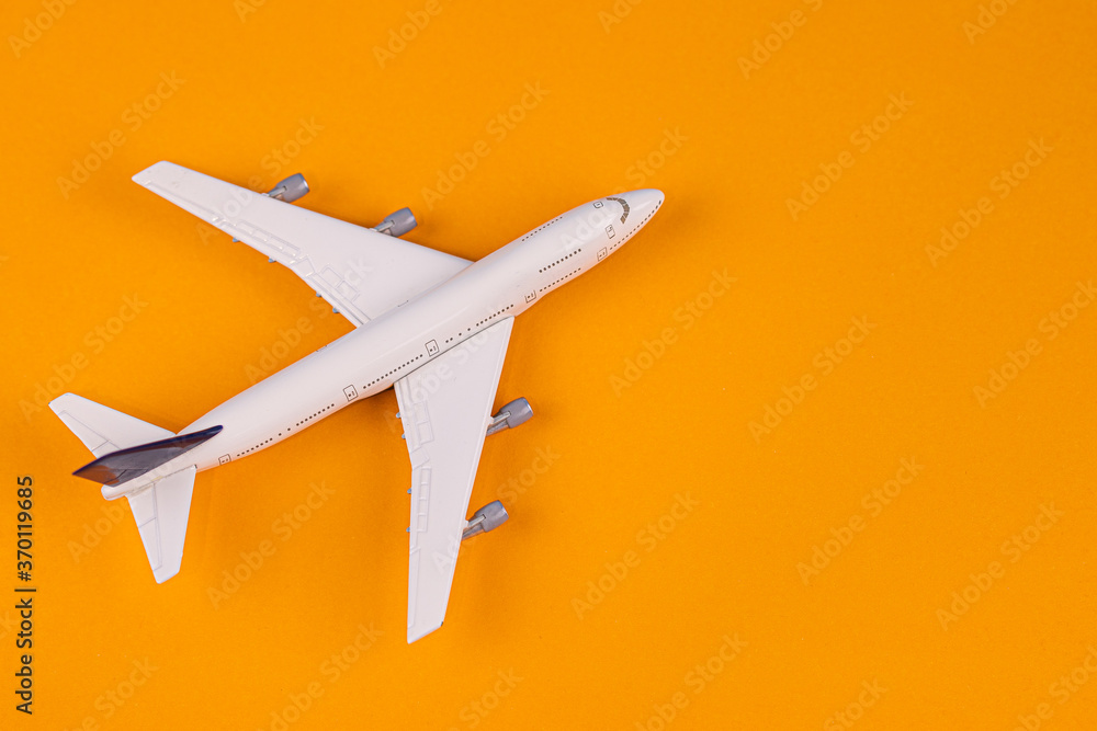 Concept of travel vacation. Top view white toy airplane isolated on orange background with copy space. Minimal think.
