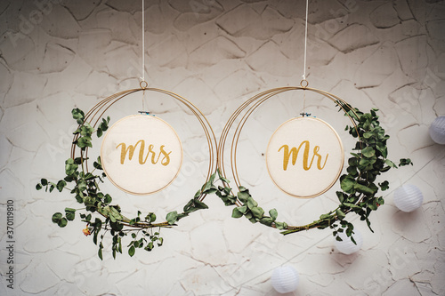 Mr and Mrs hanging wedding hoops against wall at reception photo