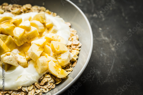 Healthy and tasty breakfast with muesli, yogurt, bananas and honey. Selective focus.

