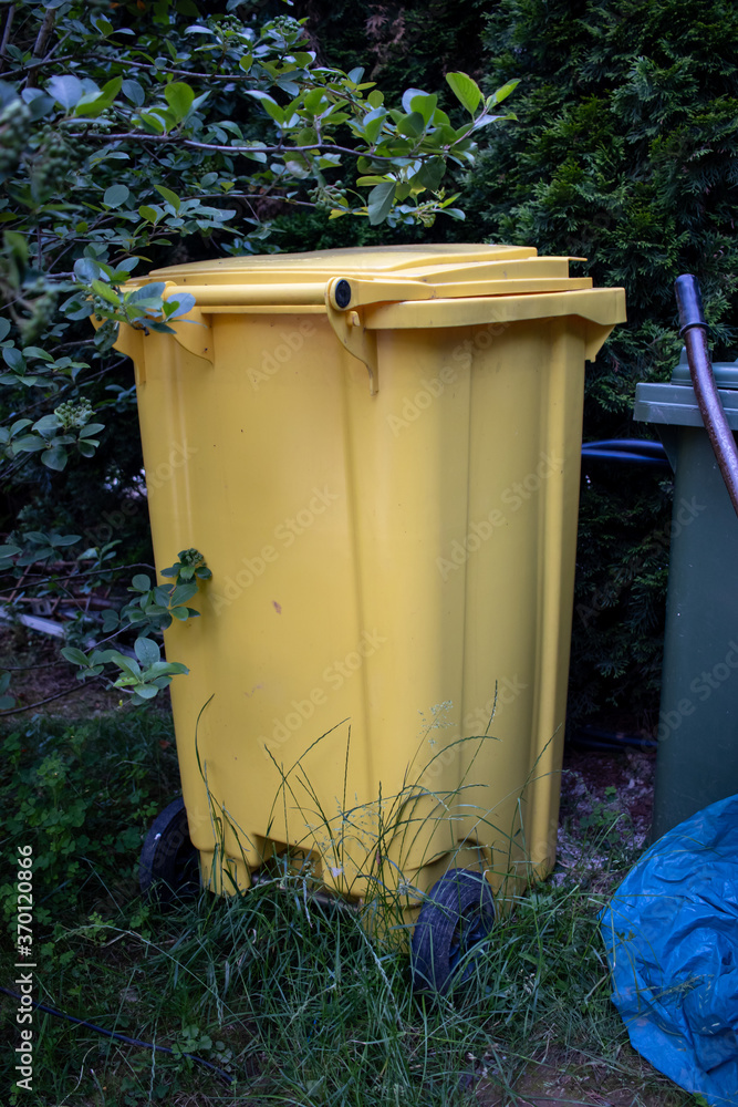 Yellow garbage container in a park AM Yellow garbage container in a park AM