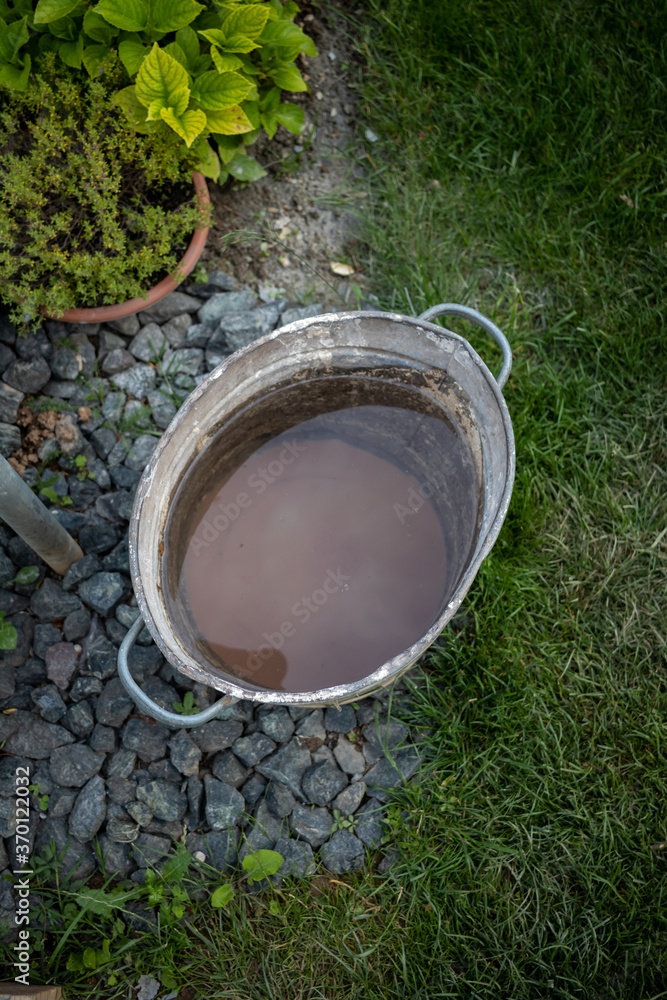 Metal bucket filled with water and dirt on the bottom of it in a park AM Metal bucket filled with water and dirt on the bottom of it in a park AM