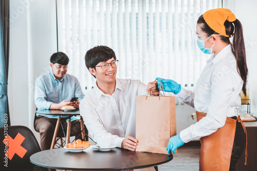 Asian staff restaurant waitress wear protective face mask working in the restaurant social distancing protect infection from coronavirus covid-19 concept