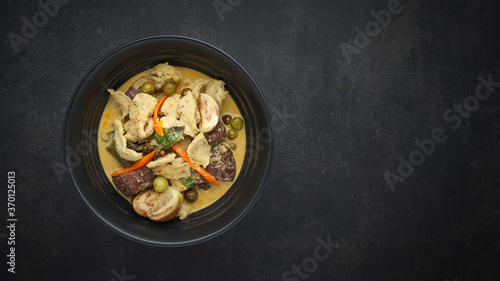 Thai traditional food sweet and spicy green curry with chicken, chicken blood curd, eggplant, small green aubergine, pea aubergine and coconut milk on dark texture background with copy space for text