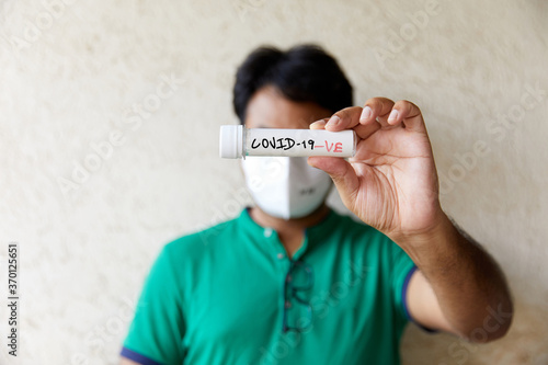Man holds a blank blood sample bottle with text written in red and white