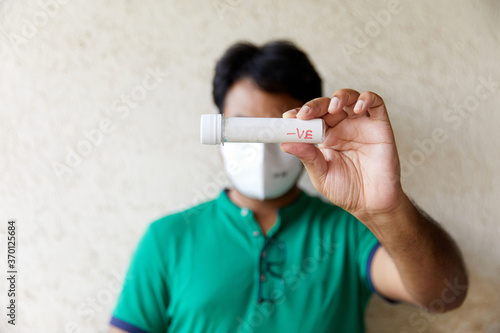 Black haired Man wearing a holds a blank blood sample bottle