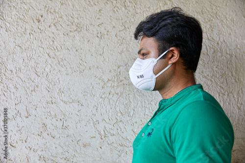 Middle-aged man with N95 mask against a beige textured wall photo