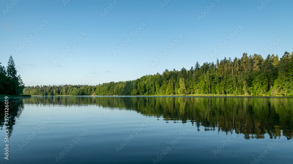 mirror image on the lake, green forest by the lake in reflection in the blue water, beauty in nature mirror image on the lake, green forest by the lake in reflection in the blue water, beauty in nature