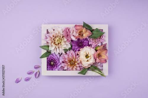 A mix of floral in a white frame on a lavender background. Romantic and fresh spring flowers with green leaves. Creative layout. Spring and wedding concept.