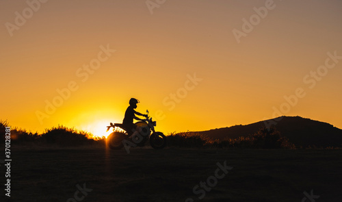 silhueta de homem a andar de moto nas montanhas ao pôr do sol