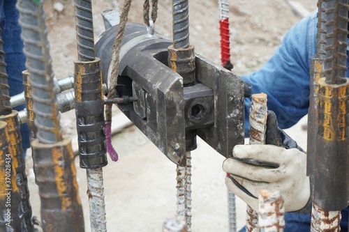 Slika na platnu Worker is using a hydraulic press to squeeze the coupler to connect the rebar in construction site