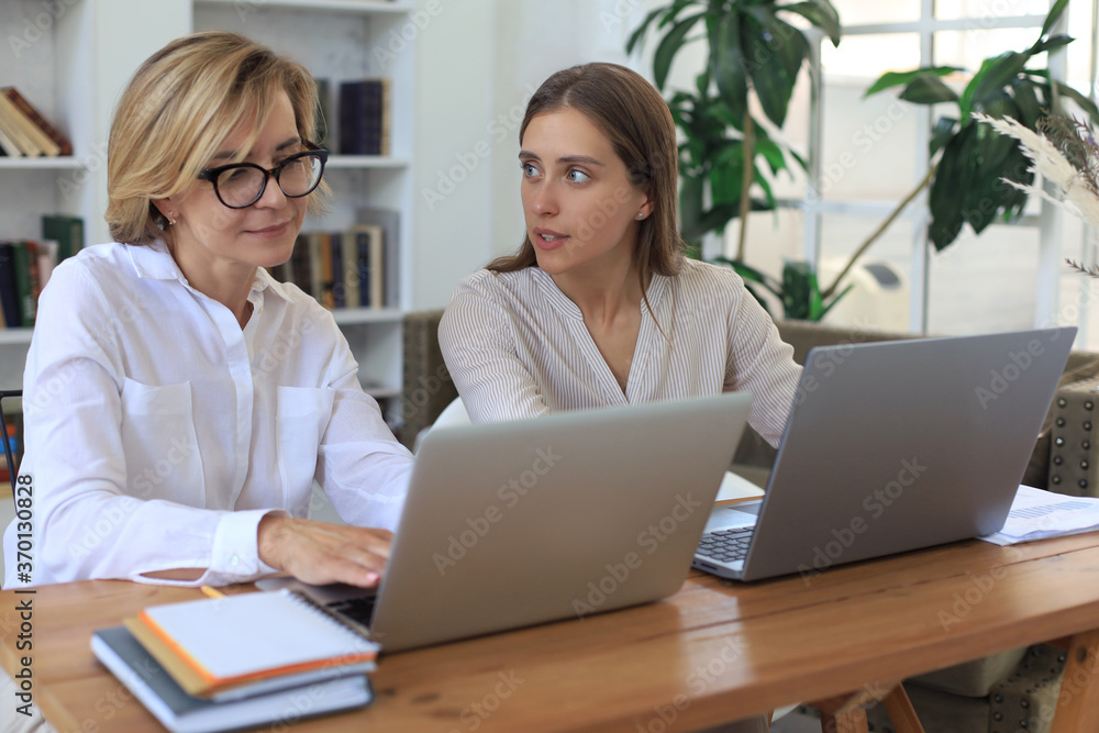 Two female collegues working with laptop and discussing new project. Two female collegues working with laptop and discussing new project.