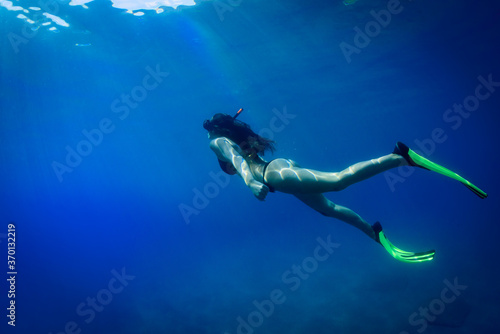 a young girl swims underwater in a transparent sea