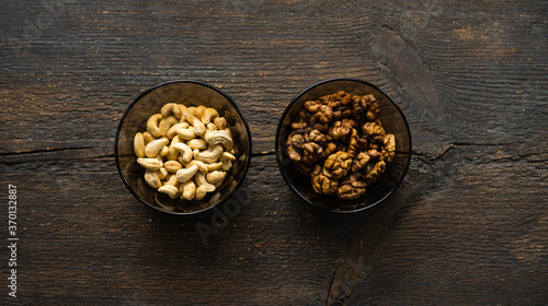 Walnut, pistachio and cashew in a small plates which standing on a black table. Nuts is a healthy vegetarian protein and nutritious food.