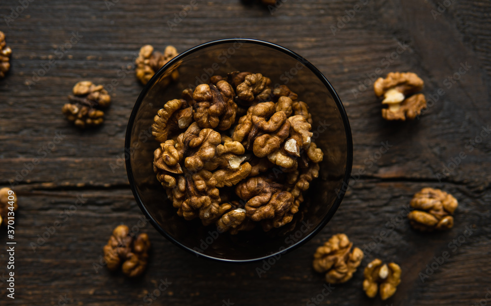 Walnut in a smale plate with scattered shelled nuts and whole nut which standing on a wooden vintage table. Walnuts is a healthy vegetarian protein nutritious food. Walnut on rustic old wood. Walnut in a smale plate with scattered shelled nuts and whole nut which standing on a wooden vintage table. Walnuts is a healthy vegetarian protein nutritious food. Walnut on rustic old wood.