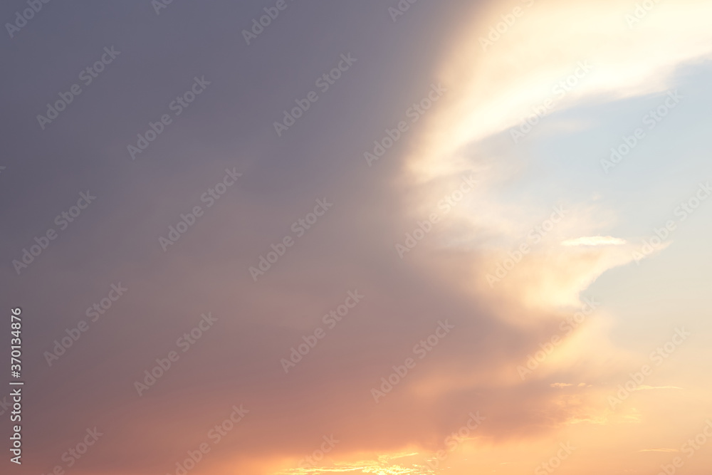 Fototapeta premium Beautiful evening blue sky at sunset with flaming bright light clouds. A warm summer evening at sunset.