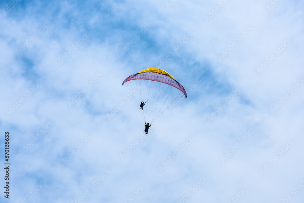 Paraglider flying against the blue sky with colorful wing above the clouds. Paraglider flying against the blue sky with colorful wing above the clouds.