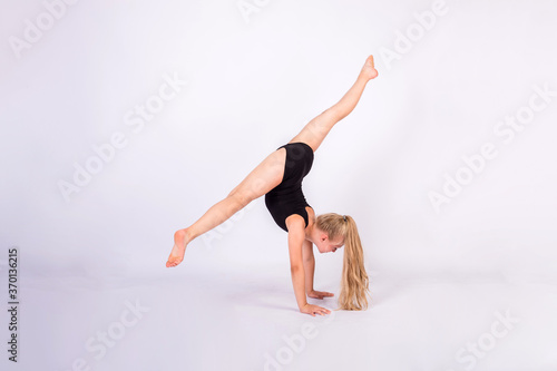 a gymnast performs splits on her hands on a white isolated background with space for text.Horizontal orientation