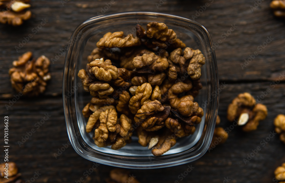 Walnut in a smale plate with scattered shelled nuts and whole nut which standing on a wooden vintage table. Walnuts is a healthy vegetarian protein nutritious food. Walnut on rustic old wood. Walnut in a smale plate with scattered shelled nuts and whole nut which standing on a wooden vintage table. Walnuts is a healthy vegetarian protein nutritious food. Walnut on rustic old wood.