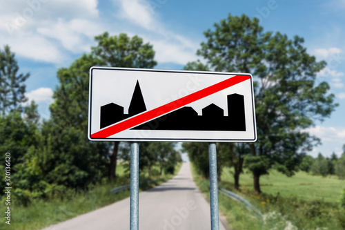 End of built-up area road sign background. Empty asphalt road and rural agriculture fields. Car travel through countryside. Speed limit road sign.