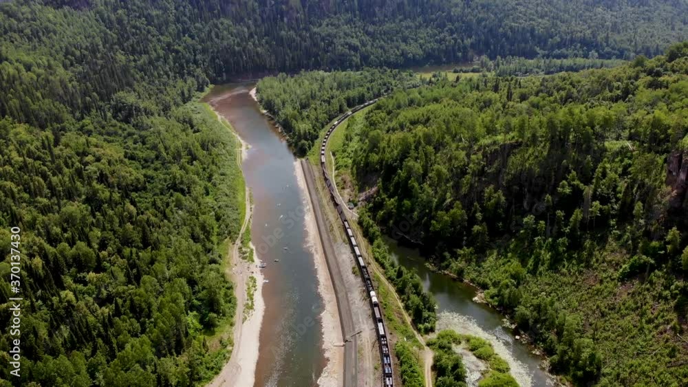 The train goes along the river and forest. Moving train from a height. The train goes along the river and forest. Moving train from a height.