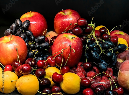 Mix of fresh berries and fruits on dark background. Peaches  apples  apricots  dark blue grapes  red cherries  blueberry   raspberries