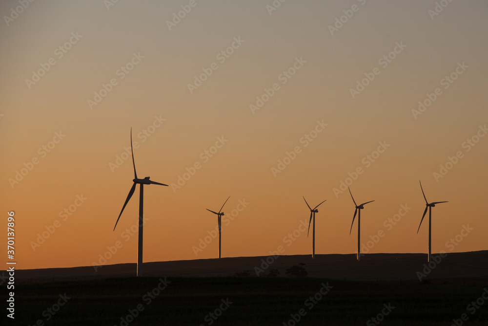 A wind farm during sunset. Turbines generating electricity. Green energy A wind farm during sunset. Turbines generating electricity. Green energy