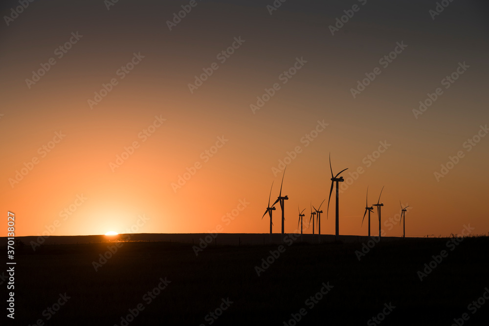 A wind farm during sunset. Turbines generating electricity. Green energy
